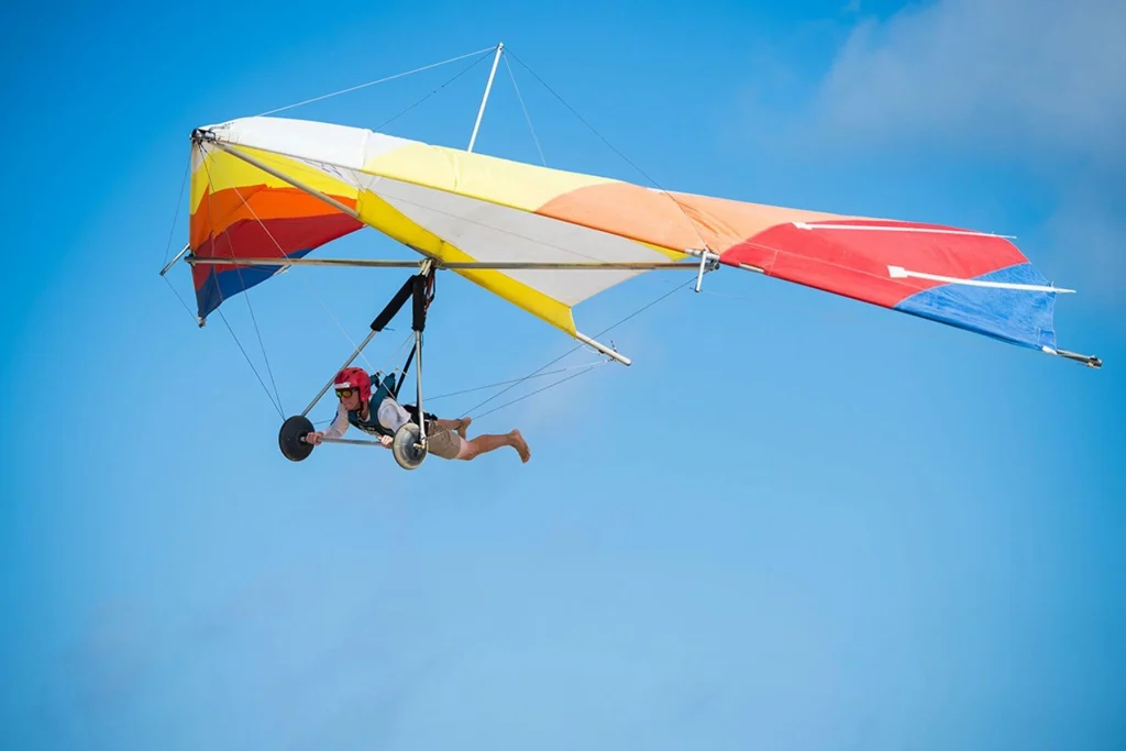 A hang glider soars freely through the clear blue sky, capturing the thrill of flight and the pure joy of adventure under the sun.