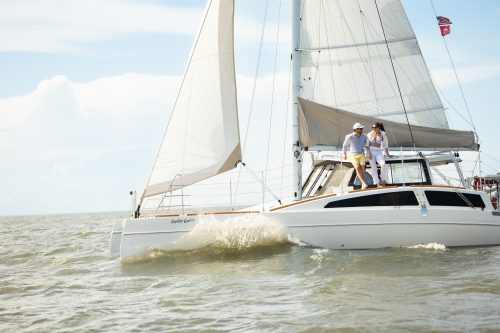 Sailing catamaran “Sophie Ann” gliding through waves with two guests aboard, coastal adventure at The Sanderling Resort.