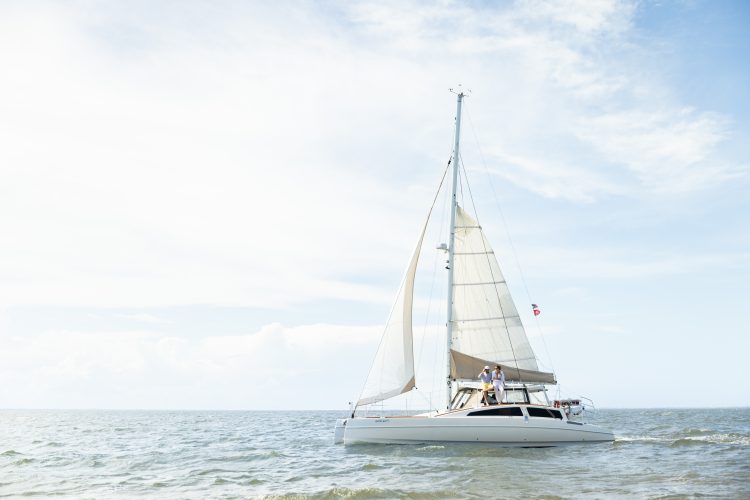Sailboat gliding on calm coastal waters under a bright sky