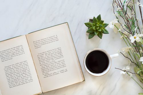 Open book with a cup of coffee and decorative plants