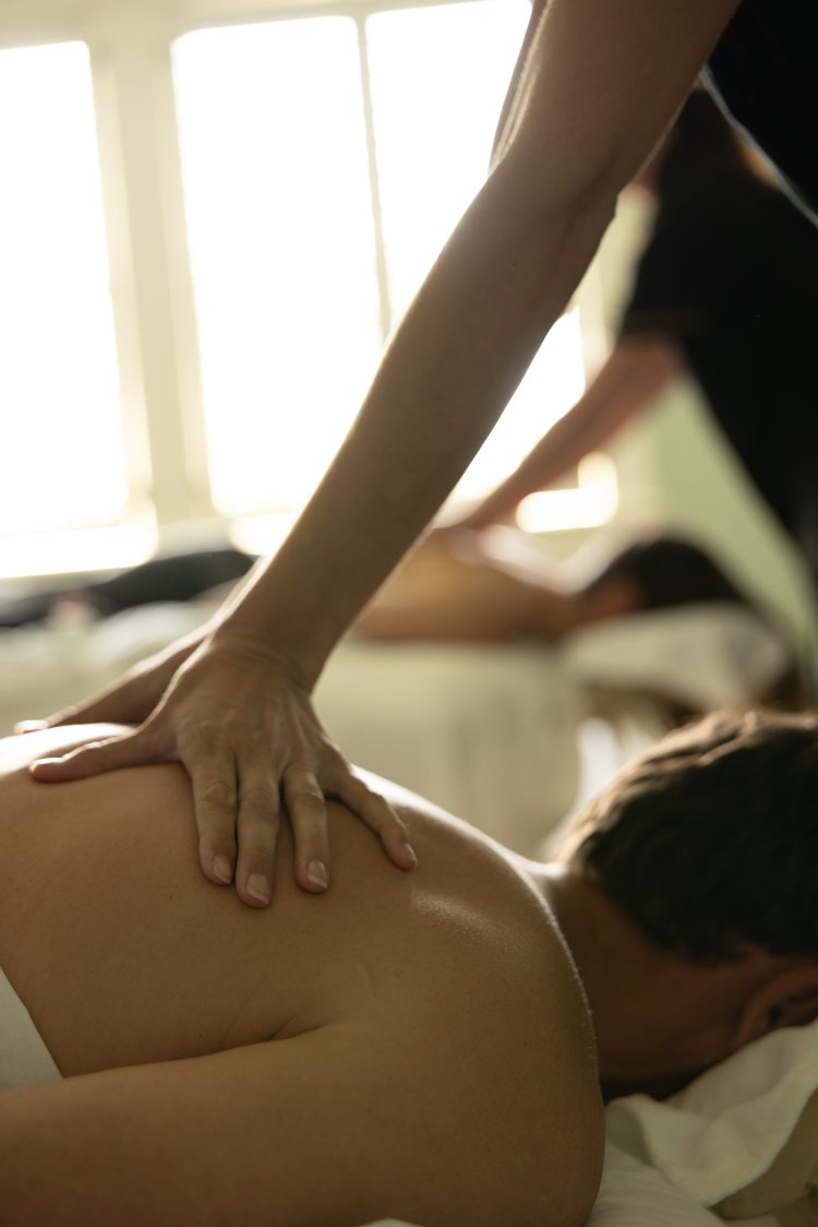 Close-up of a person receiving a relaxing back massage, with natural light streaming through windows.