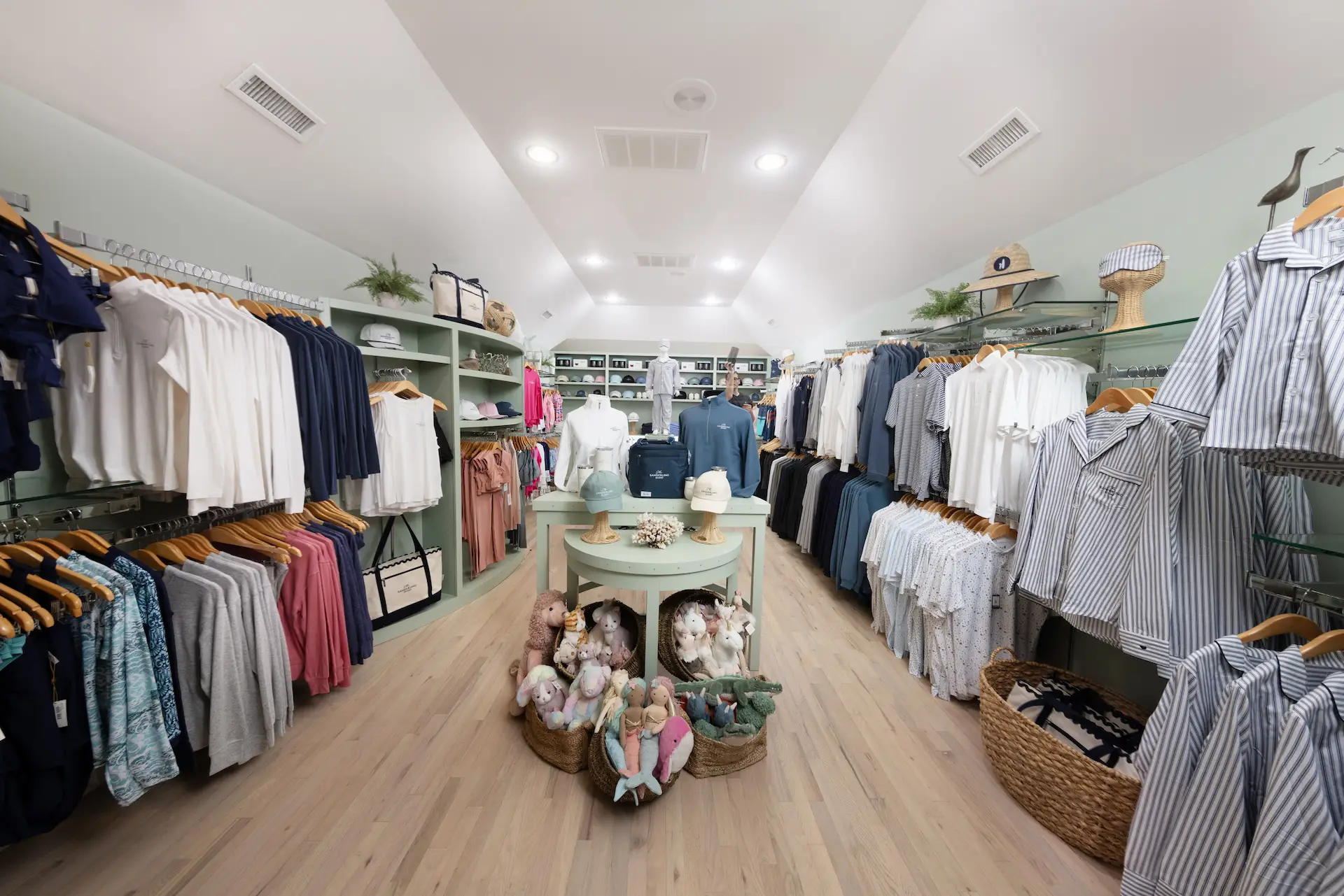 Boutique with pastel and striped clothing, plush toys, and soft lighting in a cozy layout.