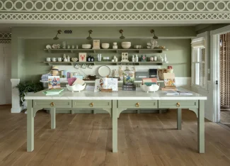 Charming boutique shop interior with green tables, shelves of ceramics, books, and decorative kitchen items.