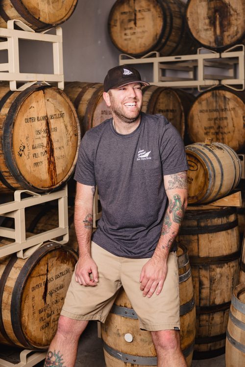 man sitting on wooden barrels in a distillery